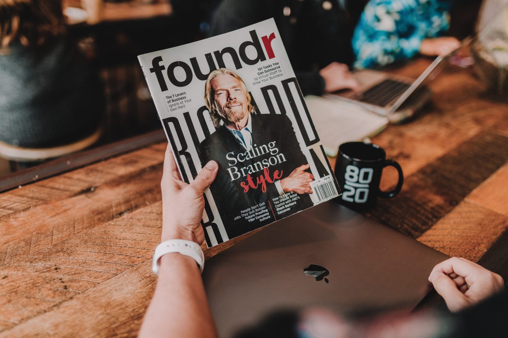 A person holding a magazine with a cover from Russel Brunson as motivation before starting to read this blog post about lessons from 10 000+ aspiring entrepreneurs